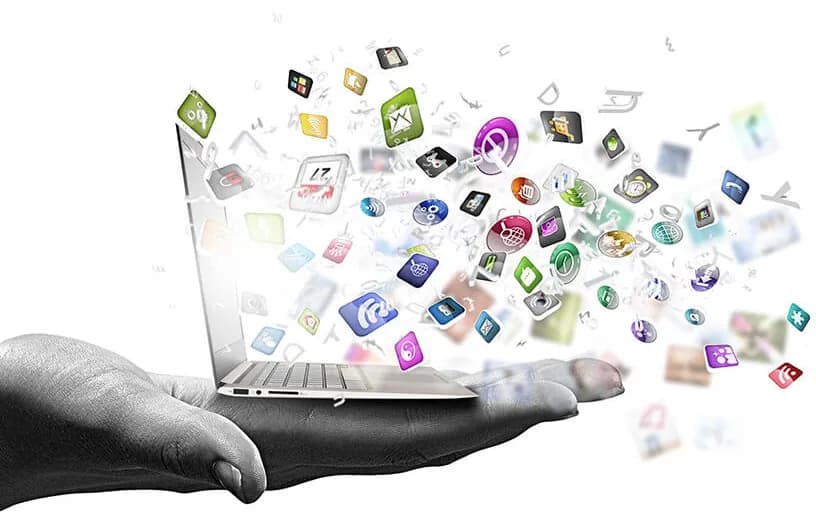 Des icônes d’applications s’élèvent d’un ordinateur portable posé sur une main