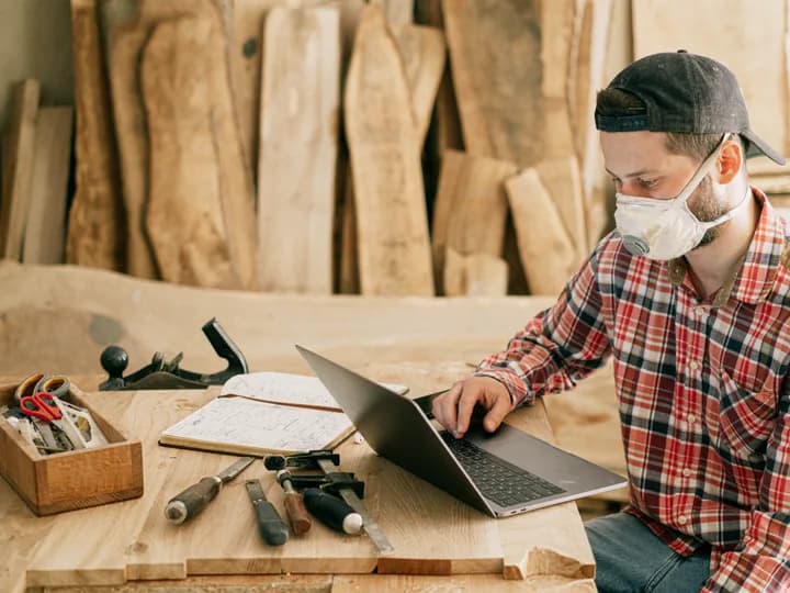 Présenter votre savoir-faire et vos services Un artisan consulte son ordinateur portable dans son atelier