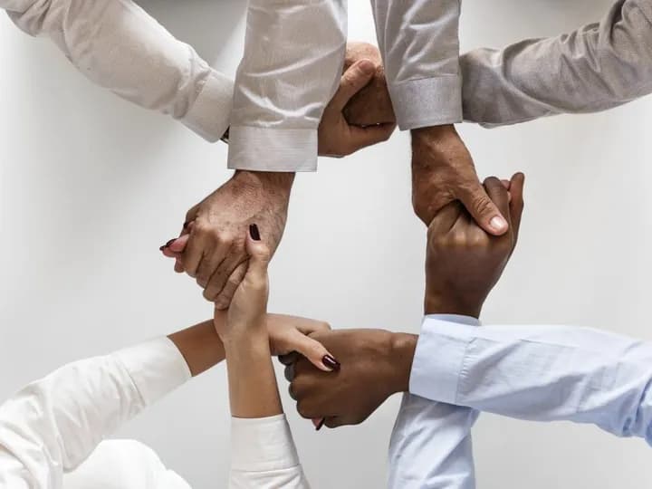 Des valeurs de coopération et d’engagement Plusieurs personnes réunissent leurs poings au centre d’un cercle