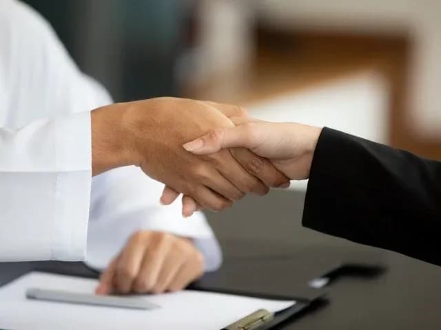 Une relation de confiance avec votre partenaire web Deux personnes se serrent la main au-dessus d’un bureau